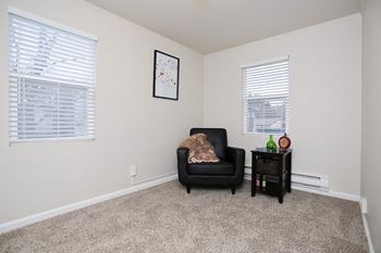 An empty living room with a black chair and a side table